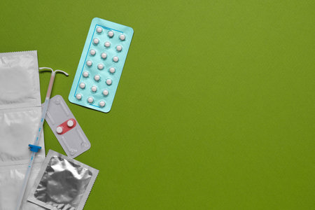 Contraception choice. Pills, condoms and intrauterine device on green background, flat lay. Space for textの写真素材