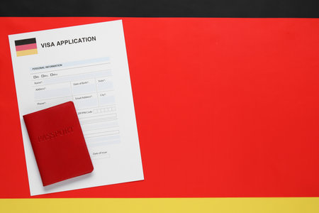 Immigration to Germany. Visa application form and passport on flag, top view. Space for textの写真素材