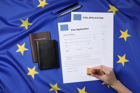 Immigration to European Union. Woman stamping visa application forms on flag, top viewの写真素材