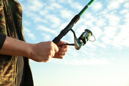 Fisherman with rod fishing under blue sky, closeupの写真素材