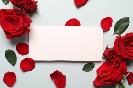 Blank card, beautiful red roses and petals on light background, flat lay. Space for textの写真素材