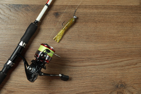 Fishing rod with spinning reel and bait on wooden background, top view. Space for textの写真素材