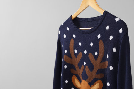 Christmas sweater hanging on rack against light background, space for textの写真素材