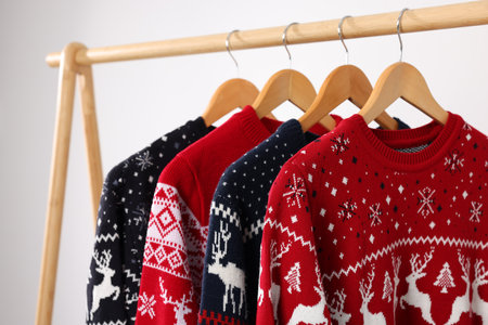Different Christmas sweaters hanging on rack against light background, closeupの写真素材