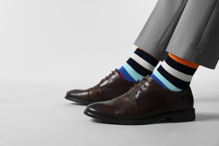 Man in stylish colorful socks, shoes and pants on white background, closeup. Space for textの写真素材