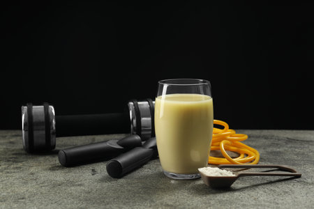 Tasty shake, sports equipment and powder on gray table against black background. Weight lossの写真素材