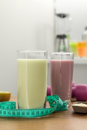 Tasty shakes, measuring tape and powder on wooden table. Weight lossの写真素材