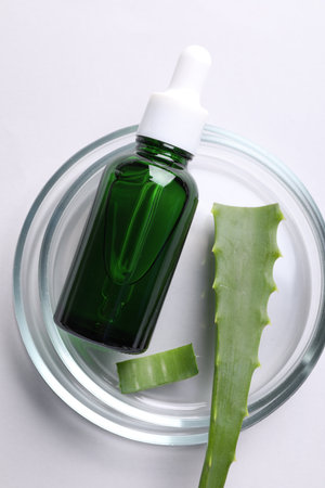Petri dish with bottle of cosmetic product and aloe vera on white background, top viewの写真素材