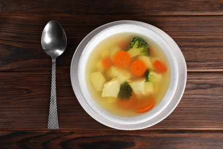 Tasty chicken soup with vegetables in bowl served on wooden table, top viewの写真素材