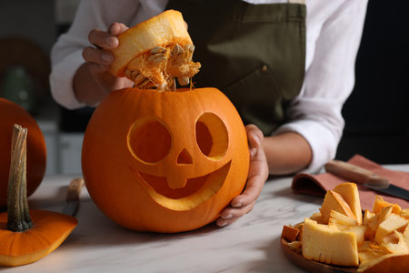 Woman with carved pumpkin for Halloween at white marble table, closeupの写真素材