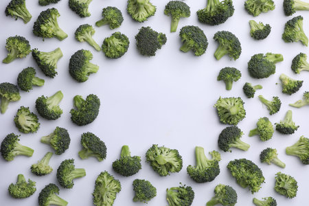 Frame made of many fresh green broccoli pieces on white background, flat lay. Space for textの写真素材