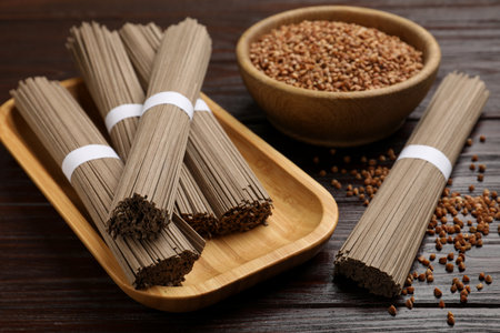 Uncooked buckwheat noodles (soba) and grains on wooden table, closeupの写真素材
