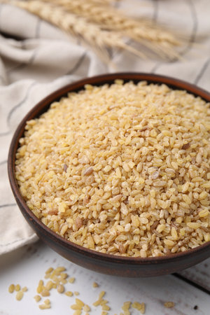Raw bulgur in bowl on white wooden table, closeupの写真素材