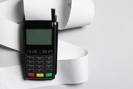 Payment terminal with thermal paper for receipt on light gray background, top view. Space for textの写真素材