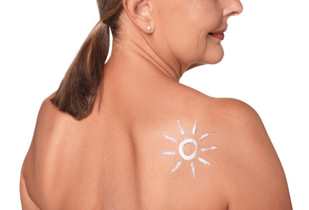 Senior woman with sun protection cream on her back isolated on white, closeupの写真素材