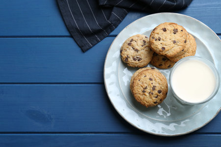 Tasty chocolate chip cookies and glass of milk on blue wooden table, flat lay. Space for textの写真素材