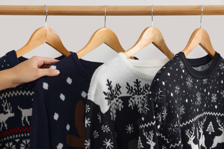 Woman choosing Christmas sweater from rack near white wall, closeupの写真素材