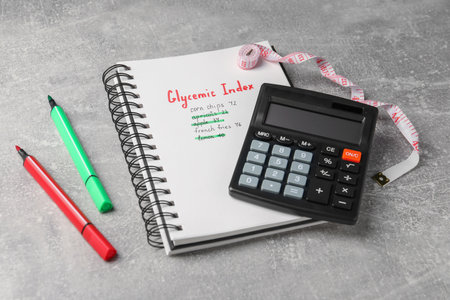 Glycemic Index. Notebook with information, markers, calculator and measuring tape on light gray tableの写真素材