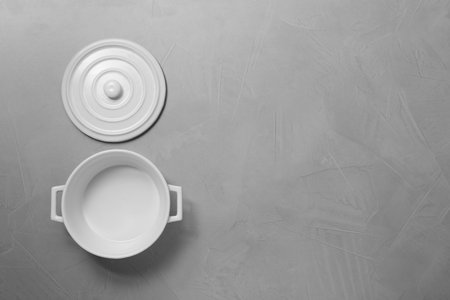 Empty ceramic pot and lid on light gray textured table, flat lay. Space for textの写真素材