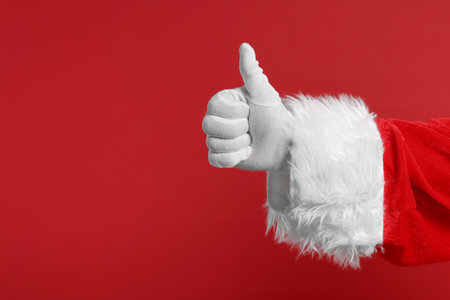 Merry Christmas. Santa Claus showing thumbs up on red background, closeup. Space for textの写真素材