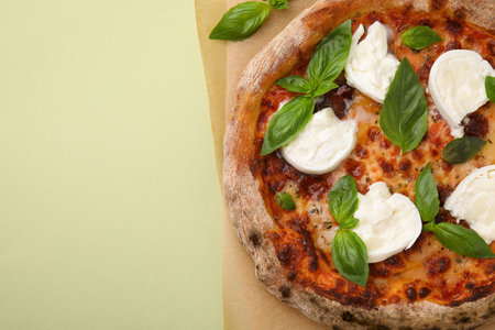 Delicious pizza with burrata cheese and basil on light green background, top view. Space for textの写真素材