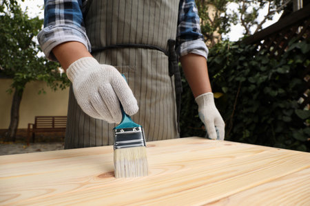 Man varnishing wooden surface with brush outdoors, closeupの写真素材