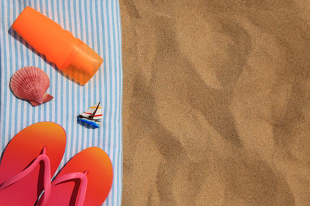 Bottle of sunscreen, flip flops and towel on sand, top view with space for text. Sun protection careの写真素材