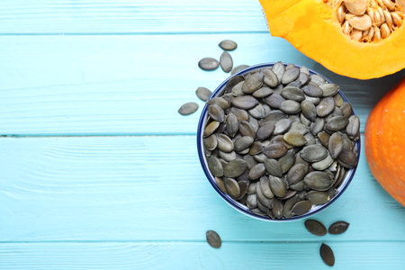 Peeled seeds and fresh pumpkin on light blue wooden table, flat lay. Space for textの写真素材