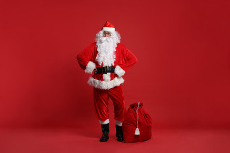 Santa Claus and bag of Christmas presents on red backgroundの写真素材