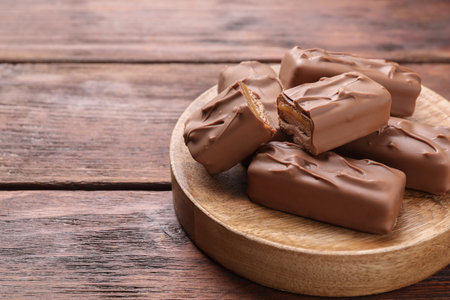 Tasty chocolate bars with nougat on wooden table, space for text