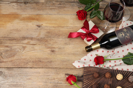 Red wine, chocolate truffles, gift box and roses on wooden table, flat lay. Space for textの写真素材