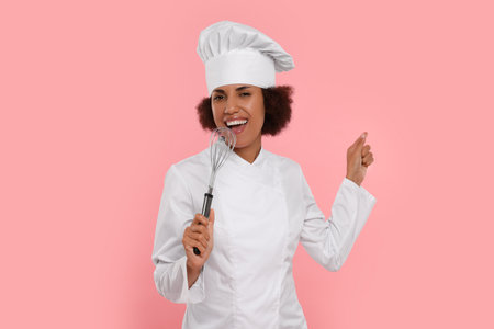 Happy female chef with whiskey singing on pink background