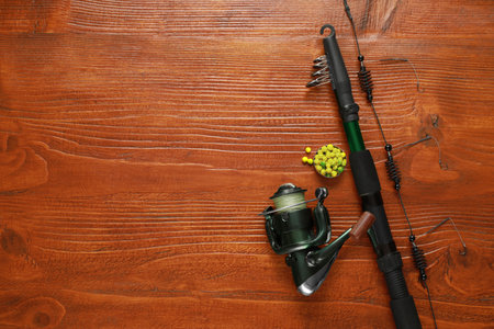 Fishing rod with reel and bait on wooden table, flat lay. Space for textの写真素材