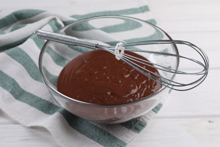 Bowl of chocolate cream and whiskey on white wooden table, closeup
