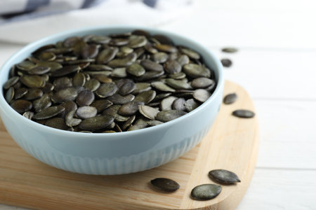 Peeled pumpkin seeds on wooden board, closeupの写真素材