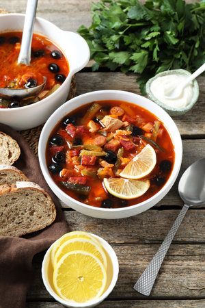Meat Solyanka soup with sausages, olives and vegetables served on wooden table, above viewの写真素材