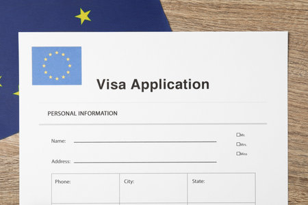 Immigration to Europe. Visa application form and flag on wooden table, top viewの写真素材