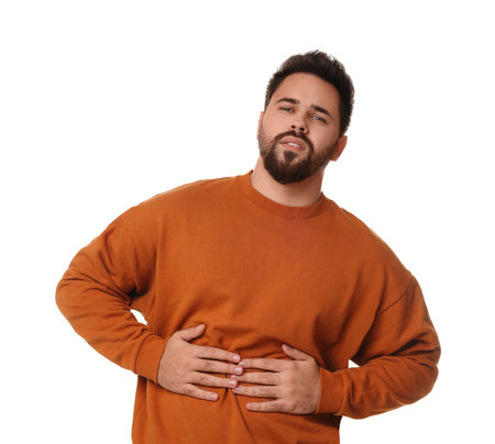 Young man suffering from stomach pain on white backgroundの写真素材