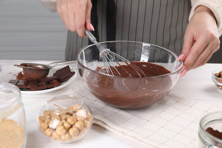 Woman mixing delicious chocolate cream with whiskey at white wooden table indoors, closeup