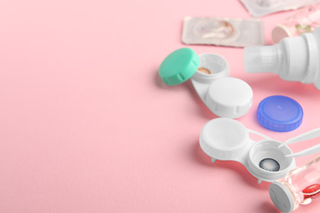Cases with color contact lenses, bottle of solution and tweeters on pink background, space for textの写真素材
