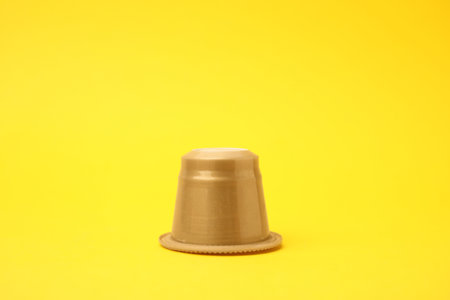 One plastic coffee capsule on yellow backgroundの写真素材