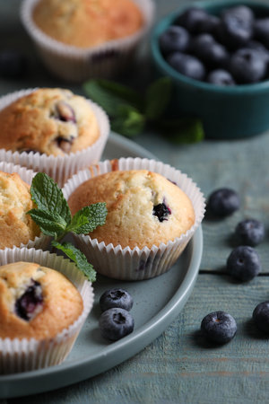 Delicious sweet muffins with blueberries and mint on light blue wooden table, closeupの写真素材