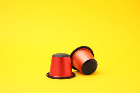 Two plastic coffee capsules on yellow backgroundの写真素材
