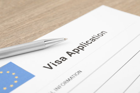 Immigration to Europe. Visa application form and pen on wooden table, closeupの写真素材