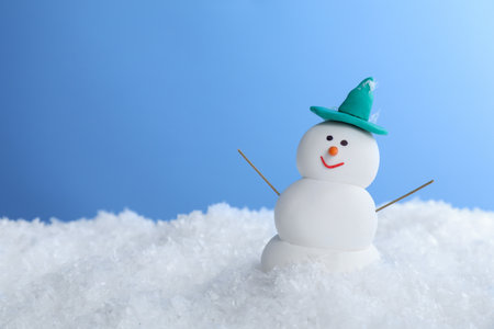 Funny snowman on snow against light blue background, space for textの写真素材