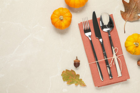 Cutlery, napkin and autumn decoration on beige marble background, flat lay with space for text. Table settingの写真素材