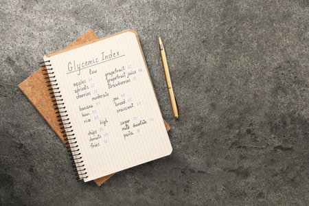 List with products of low, moderate and high glycemic index in notebook on gray table, flat lay. Space for textの写真素材