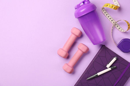 Flat lay composition with dumbbells on violet background, space for textの写真素材