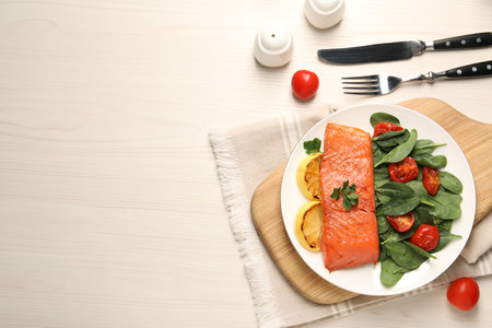 Tasty grilled salmon with basil, tomatoes and lemon on white wooden table, flat lay. Space for textの写真素材