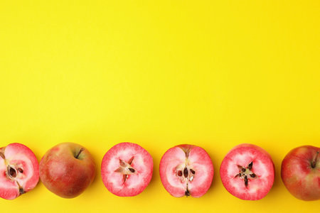 Tasty apples with red pulp on yellow background, flat lay. Space for textの写真素材